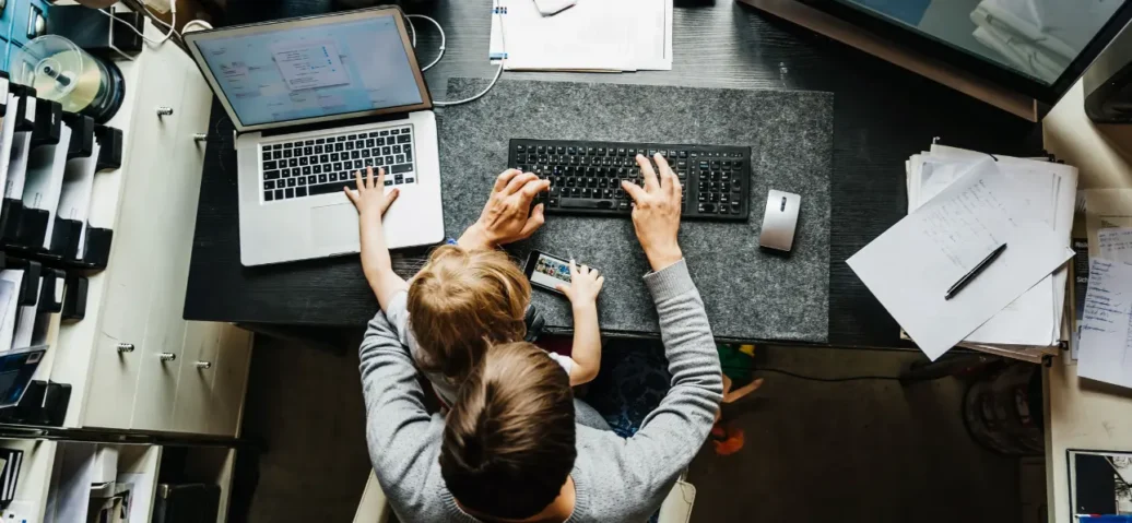 A man and a child are seated at a desk, focused on a laptop, engaged in a learning or collaborative activity.