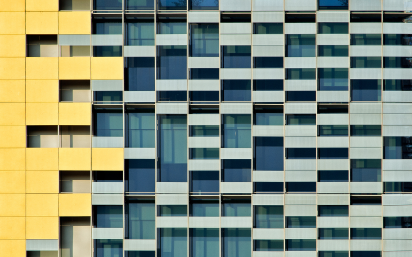 Modern building facade with geometric window patterns and yellow architectural accents.