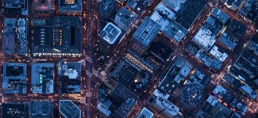 Top-down aerial view of a modern city grid and illuminated streets at night.   
