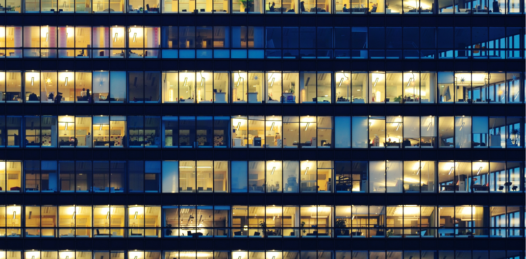 Illuminated office building windows at night showcasing modern workplace activity across multiple floors.