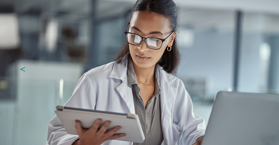 Healthcare professional reviewing information on a tablet in a medical workspace.