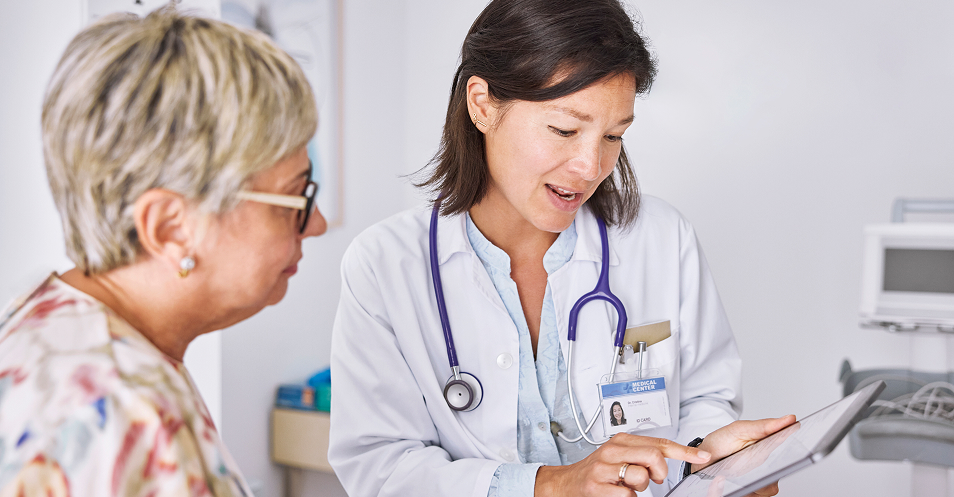 Doctor reviewing patient information on a tablet during a clinical consultation.