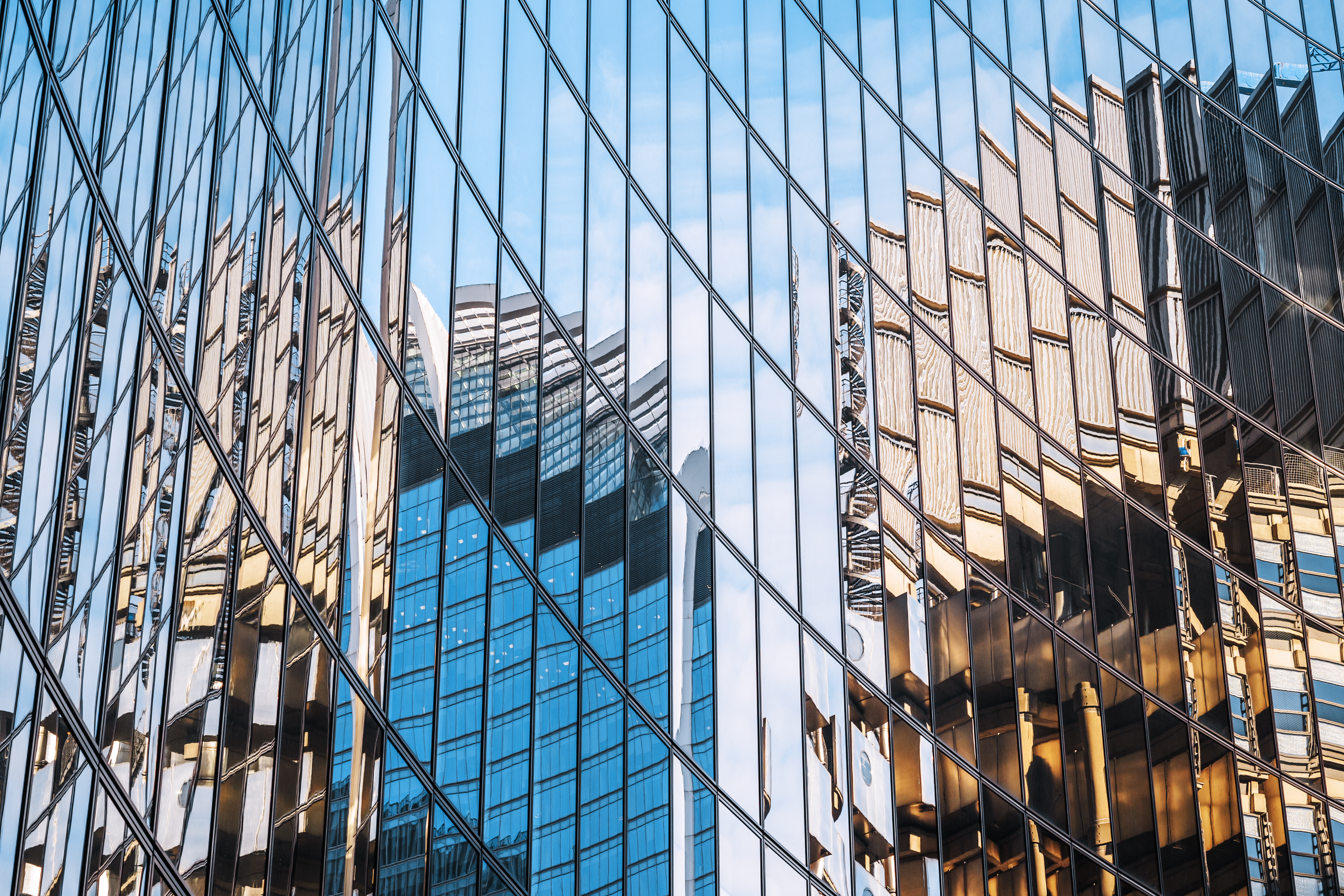 Reflection of modern city buildings on a mirrored glass facade.