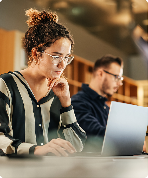 A woman and a man working on laptops in an office environment