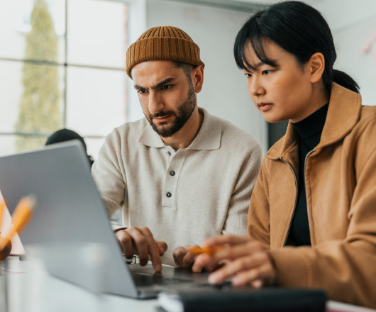 Two people intently looking at a laptop together