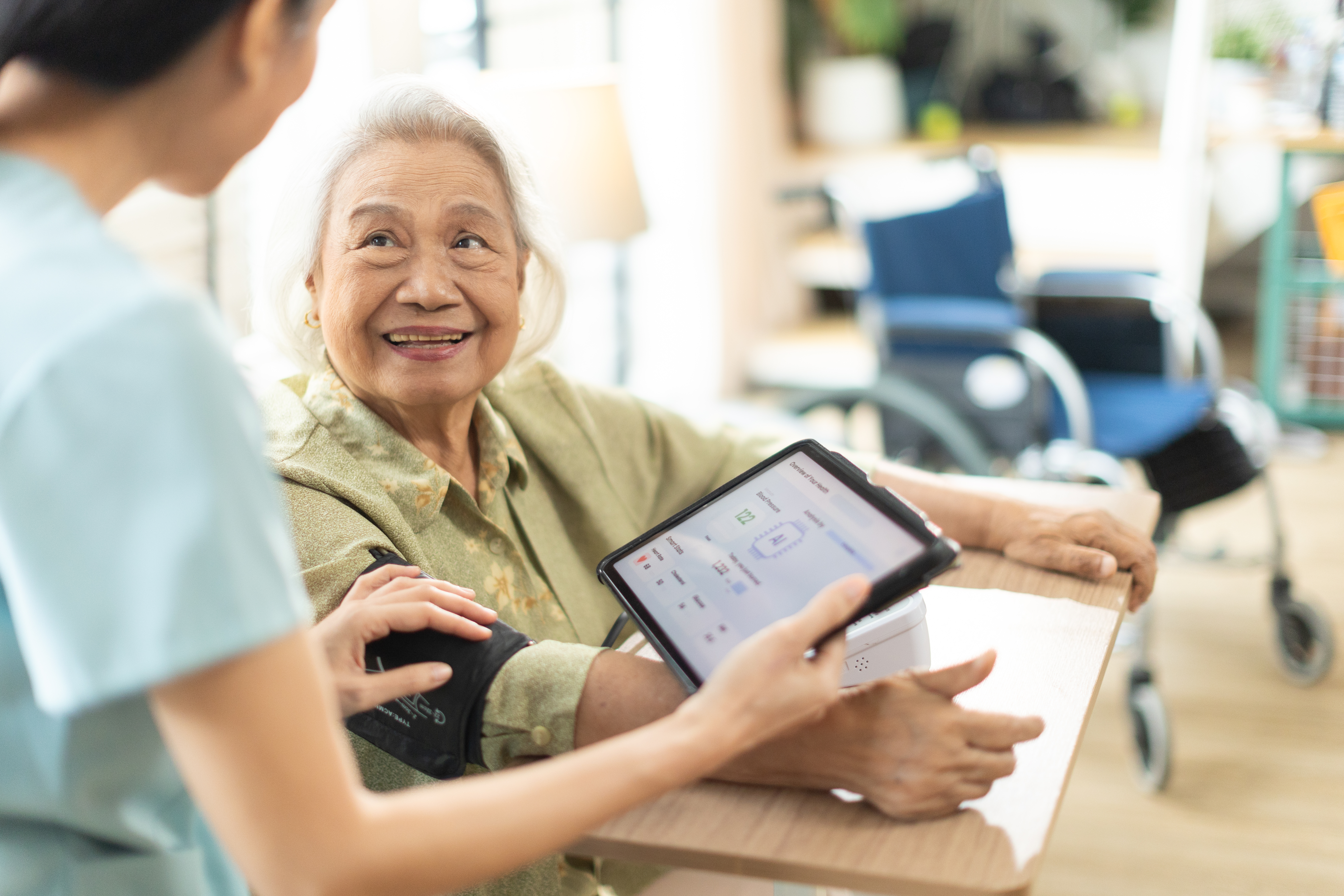 Healthcare professional checking an elderly patient's blood pressure using a digital monitor.