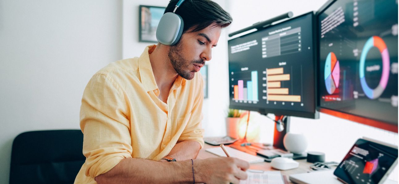 IT professional working at dual monitors displaying application code and analytics dashboards.
