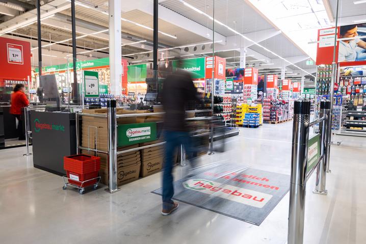 Person walking through the entrance gates of a large home improvement hardware store.