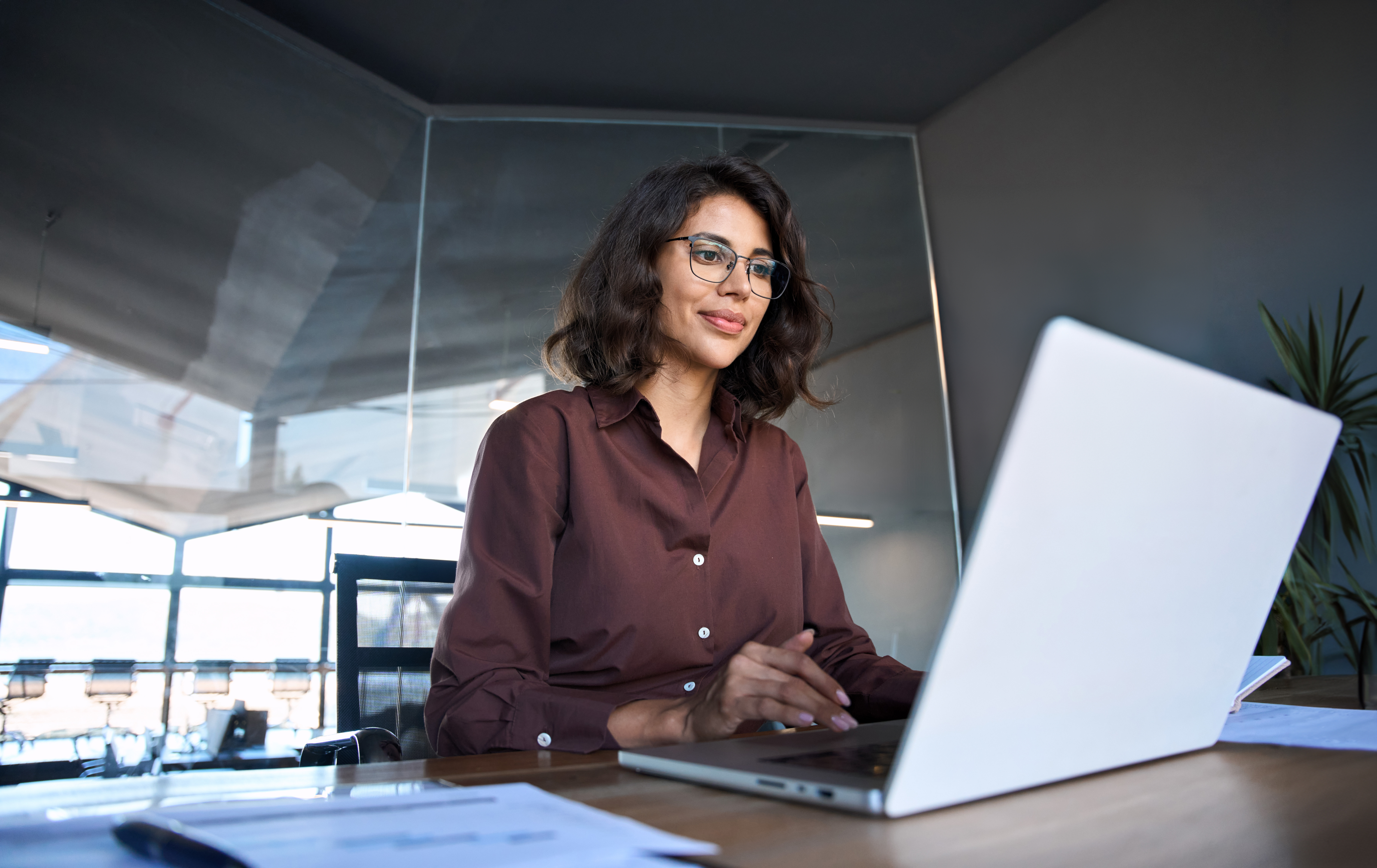 A lady with glasses using laptop in an office setting