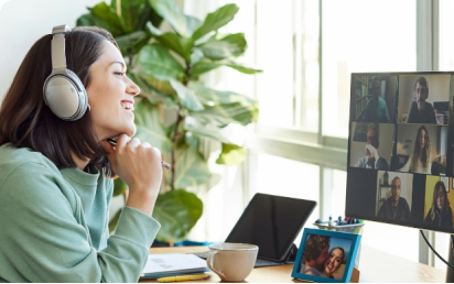 A woman with headphones participates in a video call at her desk