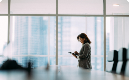 Woman in a gray suit using a tablet in a modern office with large windows