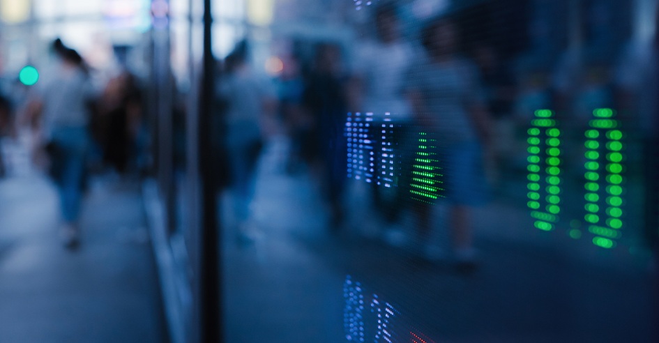 Blurred city scene with glowing digital data patterns reflected on a glass surface.