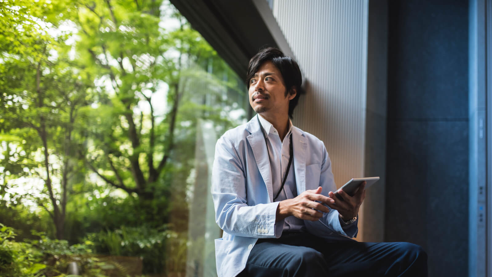Man holding a tablet looking out the window