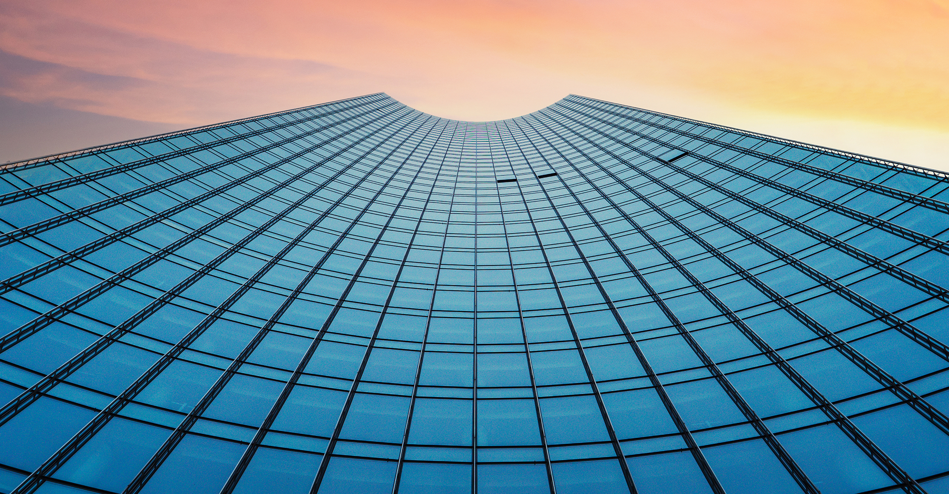 Modern glass office building reflecting the sunrise, representing digital transformation.